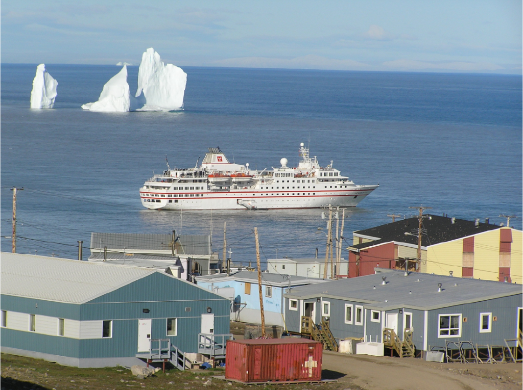 Photographie montrant le grand navire de croisière Hanseatic arrivant au village arctique de Pond Inlet (Nunavut) un jour d’été.