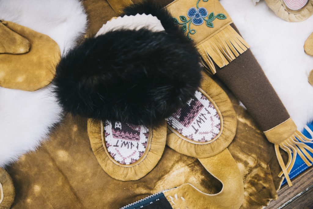 Photograph of clothing and tools made by artisans in Wekweètı̀ from tanned Caribou hide.